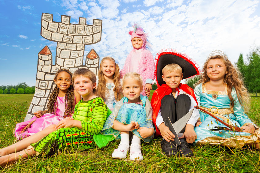 Smiling children in festival costumes sitting together near drawn tower and having fun